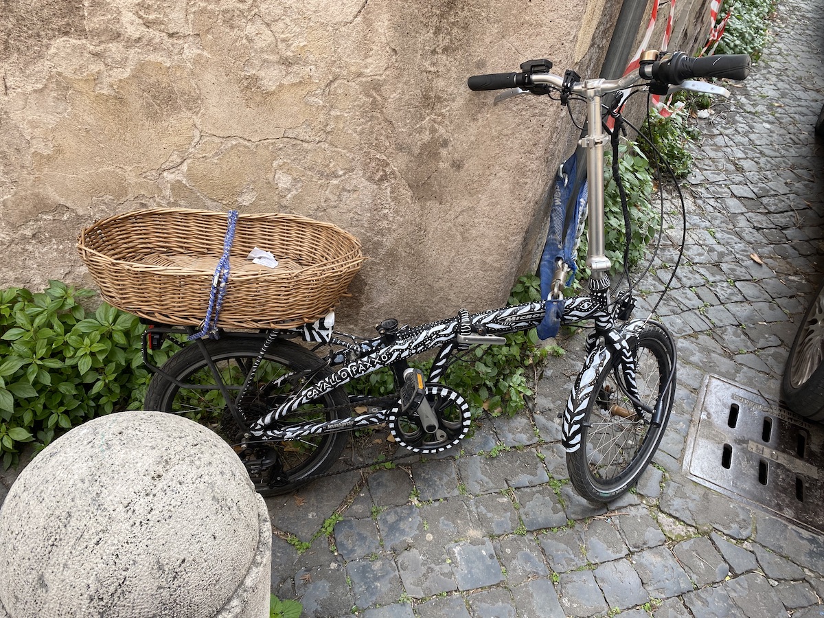 A folding bicycle painted in a razzle-dazzle fashion, labelled cavallo paxxo and with its saddle removed